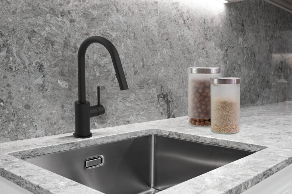This kitchen has a silver sink with a dark, matte-finished faucet. There are two containers next to the sink holding food.