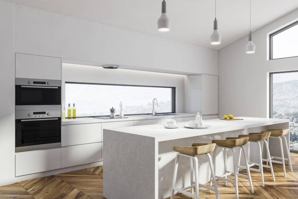 White kitchen with light wooden details, with a single-handed, curved neck faucet with polished chrome finish.