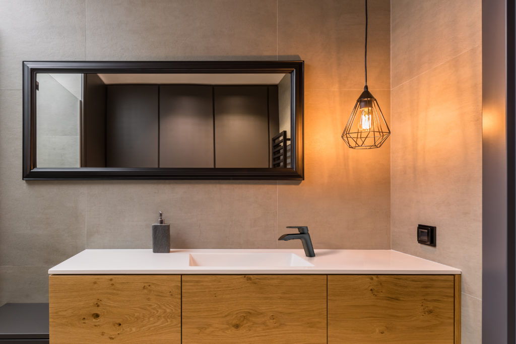 A warm colors bathroom, complemented with black details, such as black mirror frame and matte black single-handed bathroom faucet.