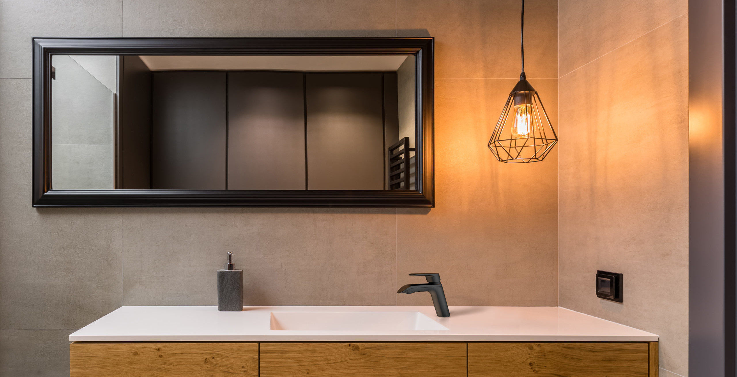 A warm colors bathroom, complemented with black details, such as black mirror frame and matte black single-handed bathroom faucet.