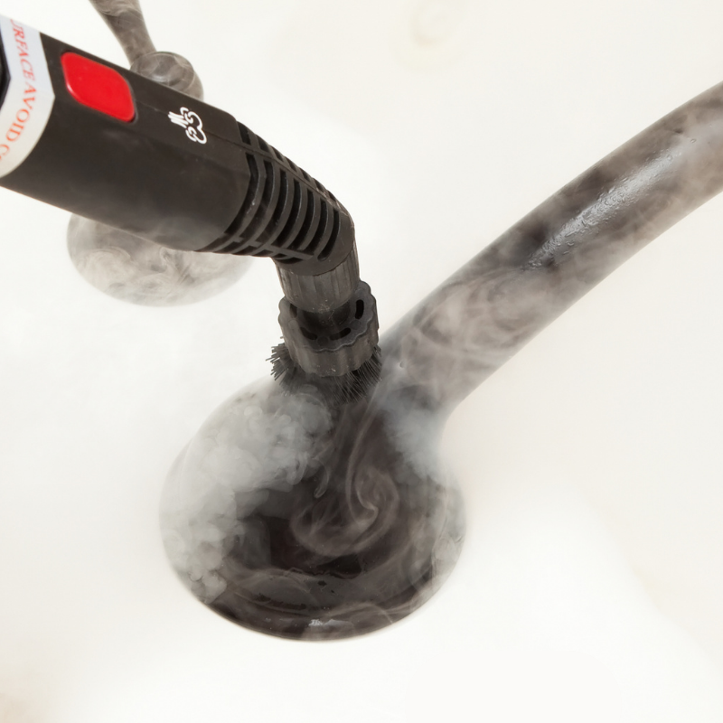A small handheld steam cleaner is used on a matte black faucet